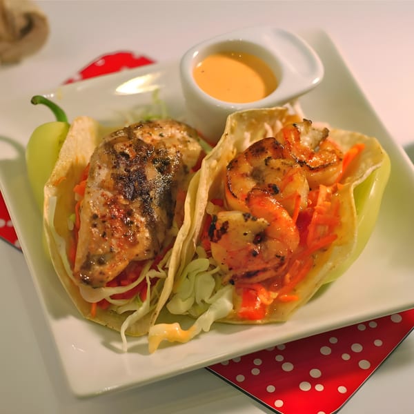 Two Fish's Wild tacos, one with grilled fish and one with shrimp, served with sauce.